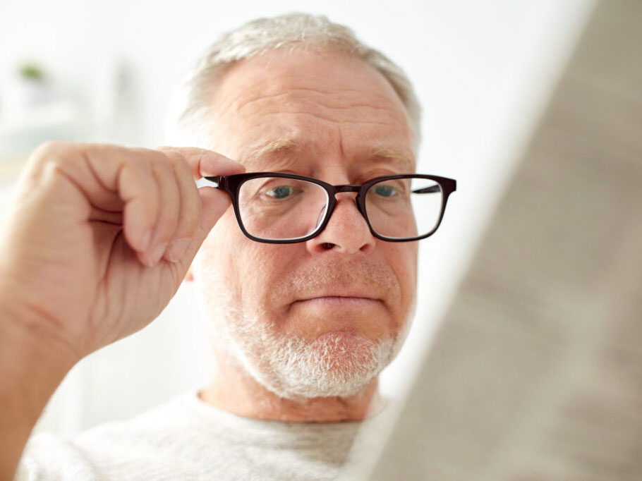 An older man with glasses holds the frame and reads a newspaper as he considers Blended LASIK eye surgery at Clearsight LASIK and Lens.